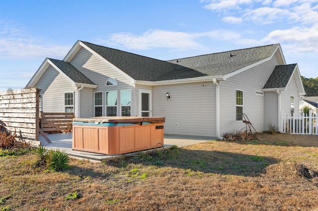 rear view of property featuring a hot tub and a lawn