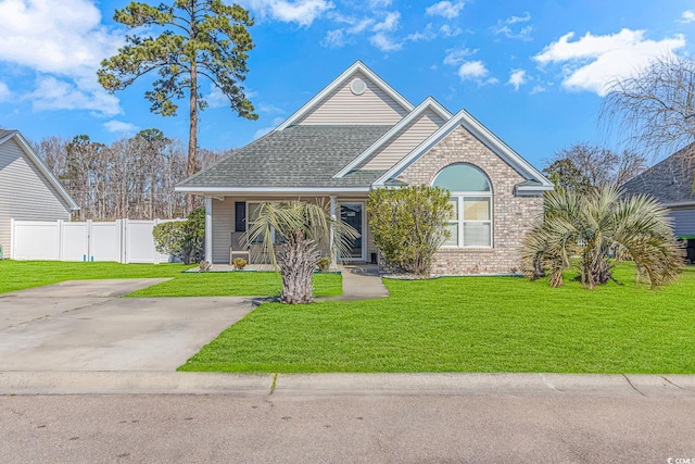 view of front of property with brick siding, a front yard, roof with shingles, and fence