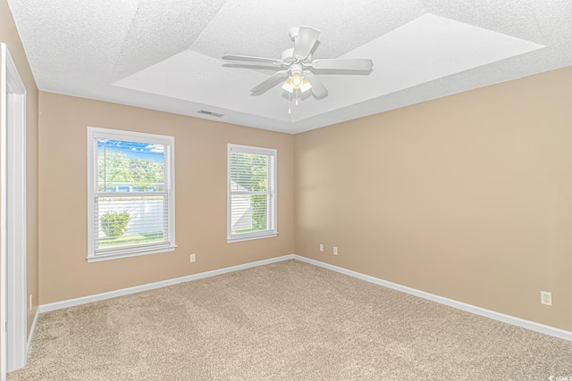 unfurnished room featuring a tray ceiling, baseboards, carpet flooring, and a textured ceiling