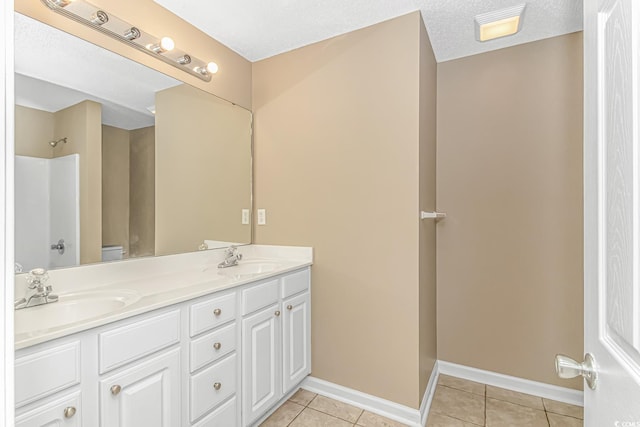 full bathroom featuring a sink, baseboards, double vanity, and tile patterned flooring