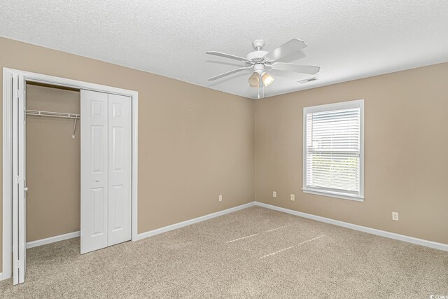 unfurnished bedroom featuring a textured ceiling, a closet, visible vents, carpet floors, and baseboards