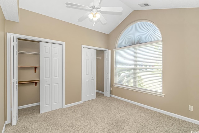 unfurnished bedroom featuring two closets, visible vents, carpet flooring, lofted ceiling, and baseboards