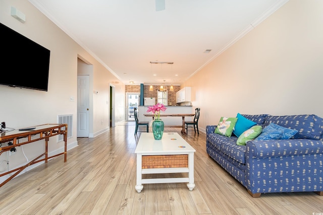 living room with light hardwood / wood-style flooring, a chandelier, brick wall, and ornamental molding