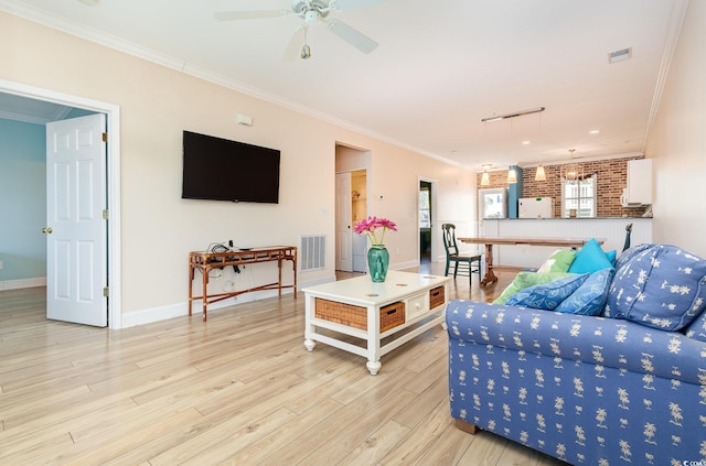 living room with track lighting, crown molding, ceiling fan, light wood-type flooring, and brick wall