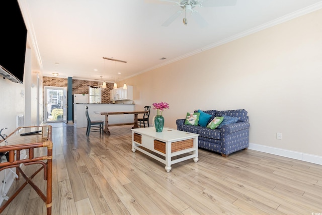 living room featuring ceiling fan, brick wall, light wood-type flooring, and ornamental molding