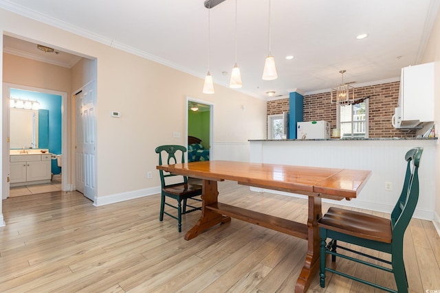 dining area featuring sink, light hardwood / wood-style flooring, crown molding, and brick wall