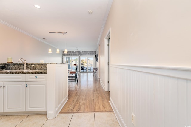 corridor featuring crown molding, sink, and light tile patterned flooring