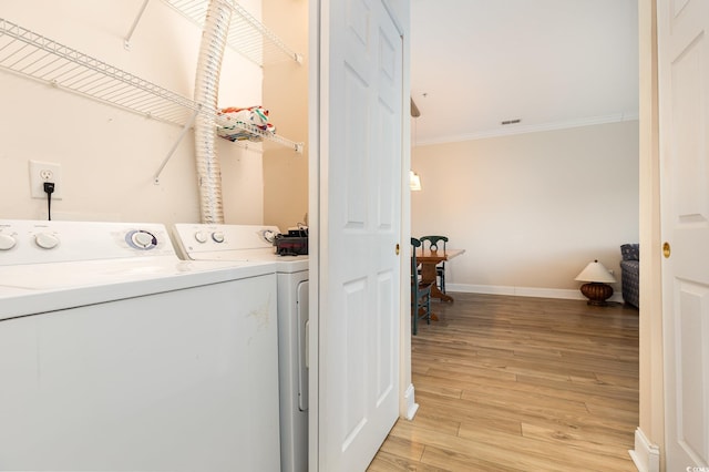 clothes washing area featuring separate washer and dryer, crown molding, and light hardwood / wood-style floors