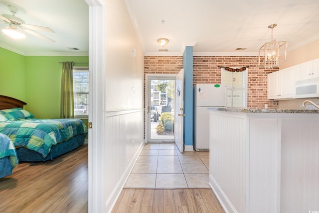 kitchen featuring white cabinets, brick wall, white appliances, and ornamental molding