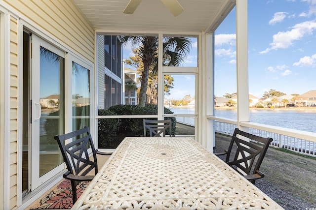 sunroom featuring ceiling fan and a water view