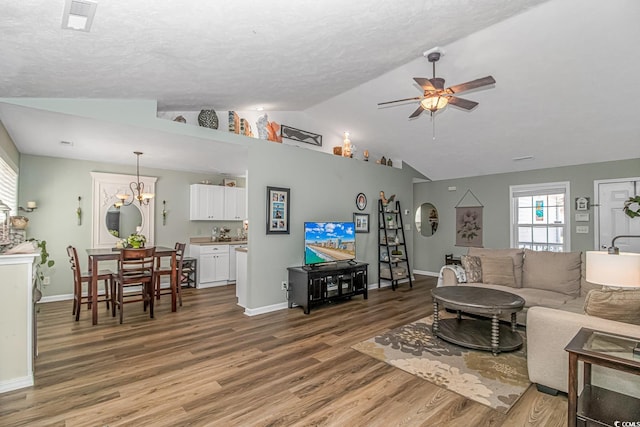 living area featuring baseboards, visible vents, a ceiling fan, lofted ceiling, and light wood-type flooring