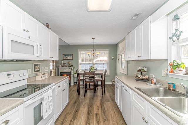 kitchen featuring white appliances, wood finished floors, light countertops, white cabinetry, and a sink