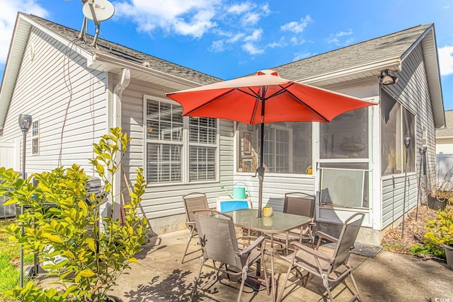 view of patio featuring outdoor dining space and a sunroom