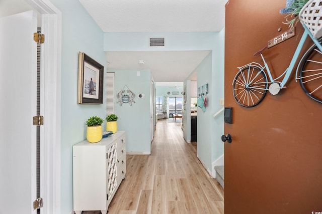 hall featuring light hardwood / wood-style flooring and a textured ceiling