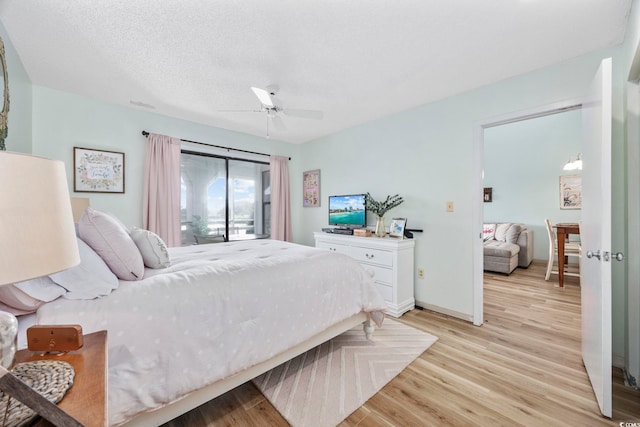 bedroom featuring access to exterior, a textured ceiling, light hardwood / wood-style flooring, and ceiling fan