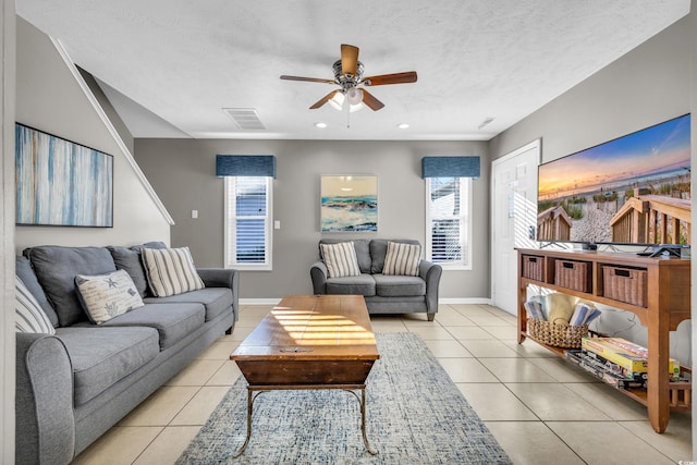 living room featuring ceiling fan, light tile patterned floors, and a textured ceiling