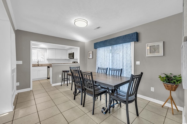 tiled dining room with a textured ceiling and sink