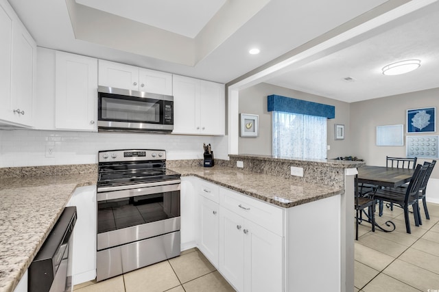 kitchen featuring white cabinetry, stainless steel appliances, light stone counters, kitchen peninsula, and light tile patterned floors