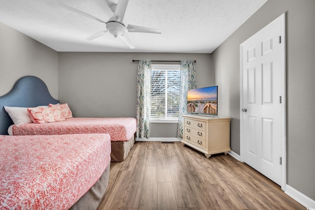 bedroom with hardwood / wood-style flooring, ceiling fan, and a textured ceiling