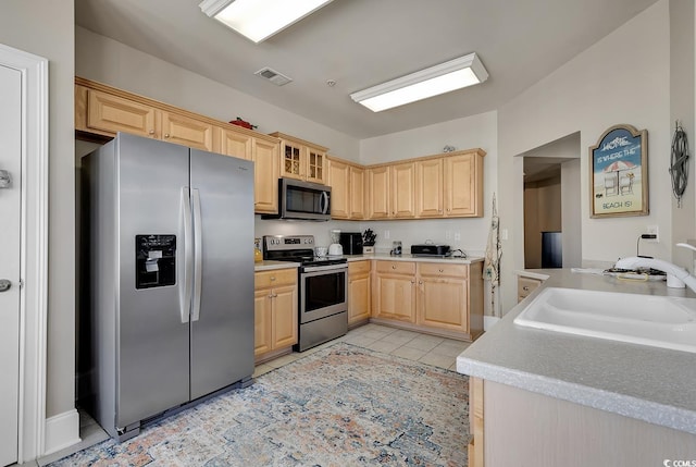 kitchen featuring stainless steel appliances, sink, light brown cabinets, and light tile patterned floors