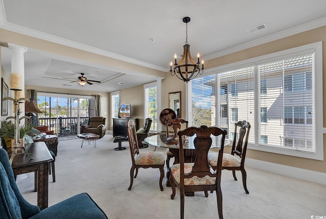 carpeted dining space with ceiling fan with notable chandelier, ornamental molding, a raised ceiling, and decorative columns