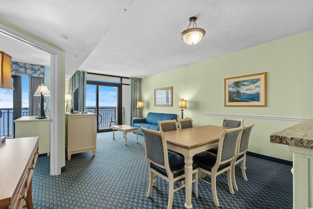 dining area featuring carpet flooring, expansive windows, a water view, and a textured ceiling