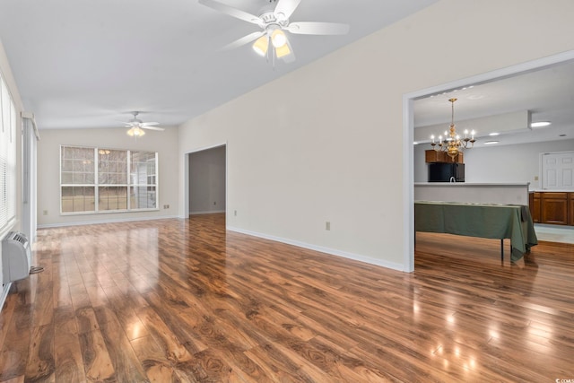 unfurnished living room featuring wood-type flooring, an AC wall unit, and ceiling fan with notable chandelier