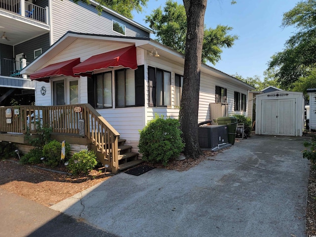 view of front of property with an outbuilding, central AC unit, and a shed