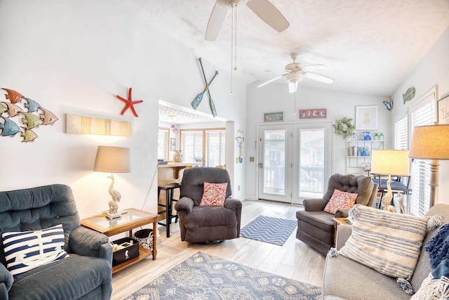 living room featuring a textured ceiling, light hardwood / wood-style flooring, and lofted ceiling