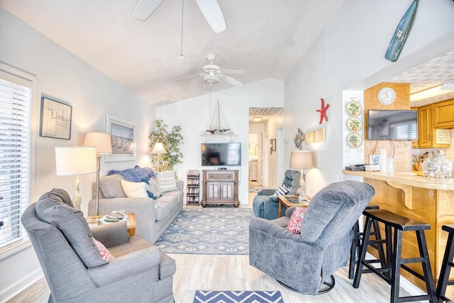 living room featuring a textured ceiling, ceiling fan, light hardwood / wood-style floors, and vaulted ceiling