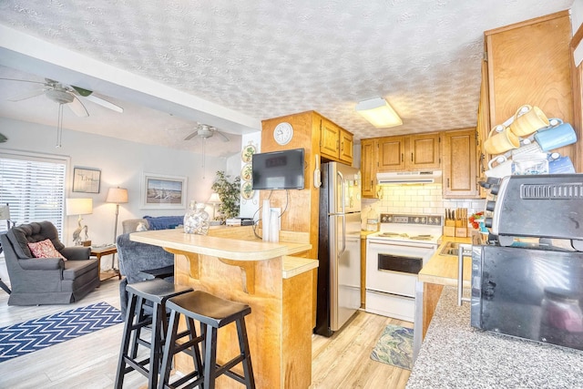 kitchen with light wood finished floors, freestanding refrigerator, range hood, light countertops, and white electric range