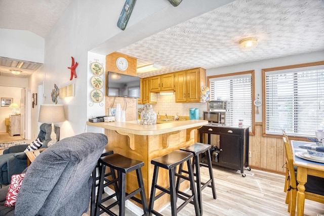 kitchen featuring vaulted ceiling, a textured ceiling, and light wood-type flooring