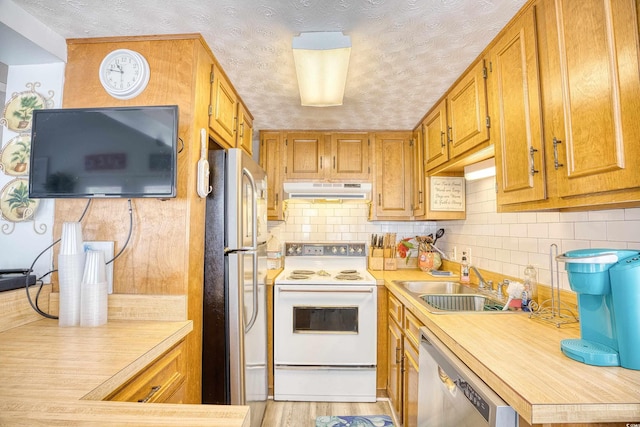 kitchen with a textured ceiling, sink, light hardwood / wood-style floors, and white appliances