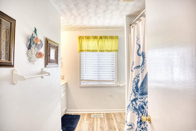 bathroom featuring baseboards, visible vents, wood finished floors, curtained shower, and a textured ceiling