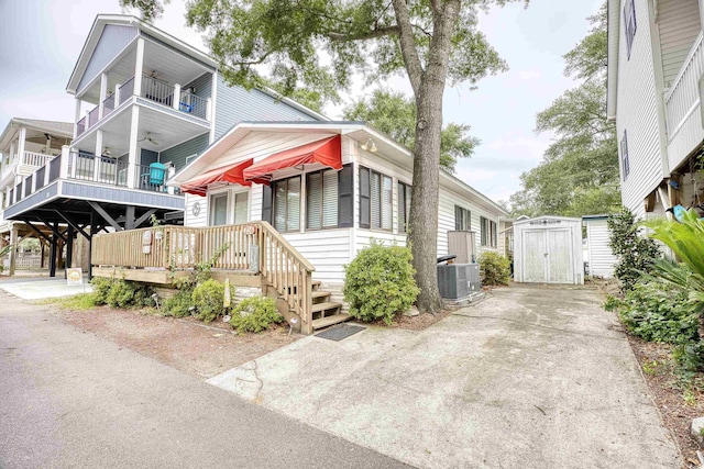 view of front facade featuring a balcony, a shed, and central AC unit