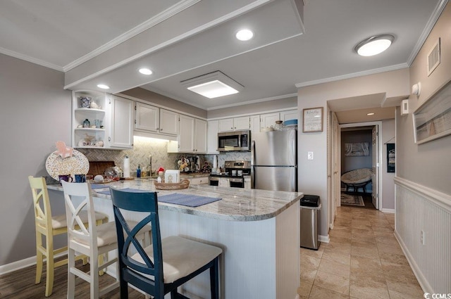 kitchen with a peninsula, a kitchen breakfast bar, white cabinets, appliances with stainless steel finishes, and open shelves