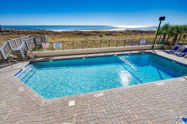 community pool with a water view and fence