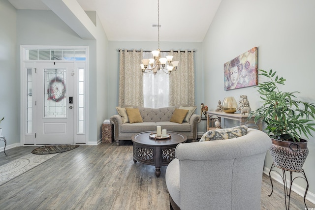 living room featuring hardwood / wood-style floors, lofted ceiling, and an inviting chandelier