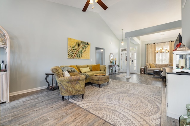 living room with hardwood / wood-style floors, ceiling fan with notable chandelier, high vaulted ceiling, and ornate columns