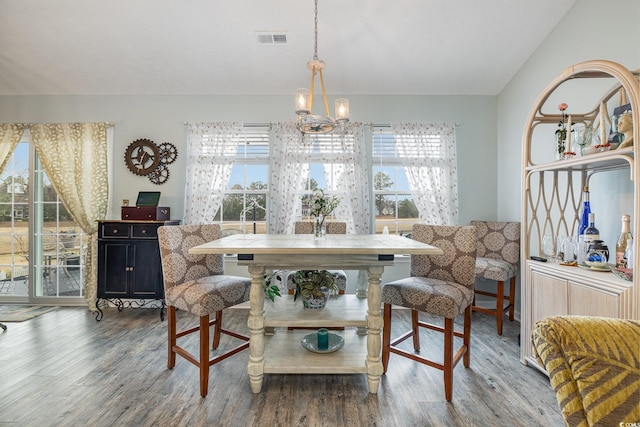 dining space with hardwood / wood-style flooring, an inviting chandelier, and a wealth of natural light