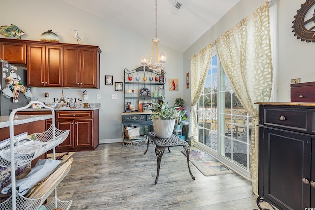 interior space with hardwood / wood-style flooring, an inviting chandelier, and vaulted ceiling