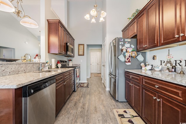 kitchen with hanging light fixtures, sink, stainless steel appliances, and an inviting chandelier