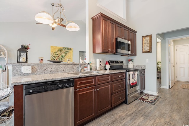 kitchen featuring high vaulted ceiling, sink, light hardwood / wood-style flooring, appliances with stainless steel finishes, and a chandelier