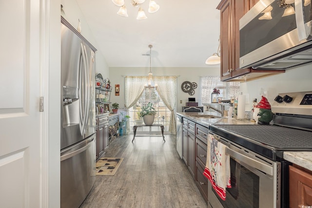 kitchen with dark wood-type flooring, sink, decorative light fixtures, a notable chandelier, and stainless steel appliances