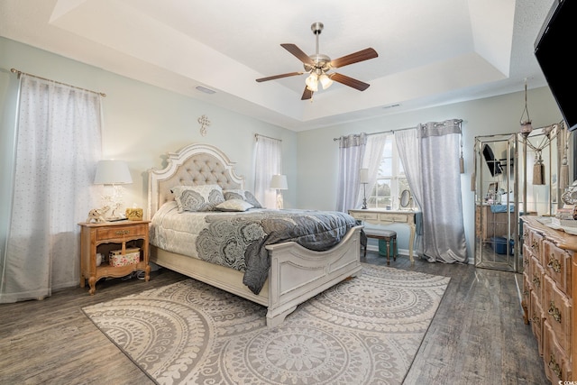 bedroom featuring ceiling fan, a raised ceiling, and wood-type flooring