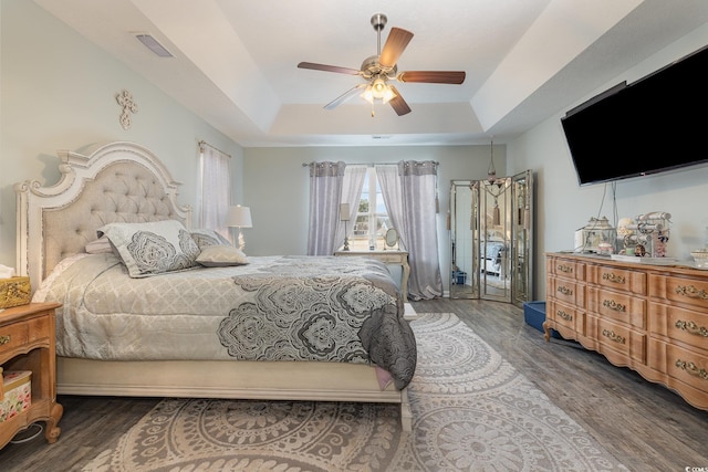 bedroom with hardwood / wood-style floors, a tray ceiling, and ceiling fan