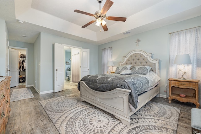 bedroom featuring a raised ceiling, ceiling fan, a spacious closet, and hardwood / wood-style flooring