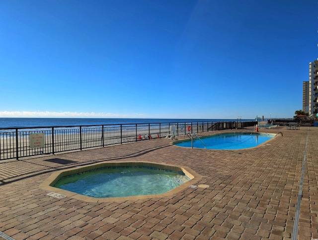 view of pool featuring a water view and a hot tub