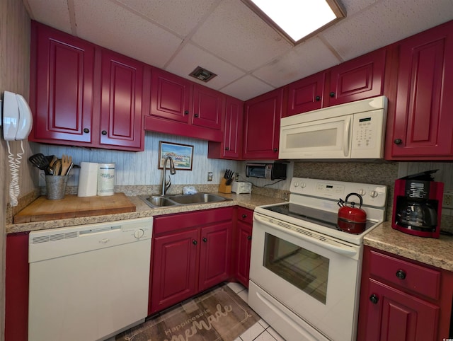 kitchen featuring dark tile patterned flooring, a drop ceiling, white appliances, and sink