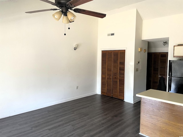 interior space featuring dark hardwood / wood-style floors, ceiling fan, and a high ceiling